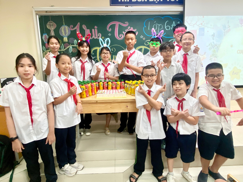 A group of students in uniform standing in front of a table

Description automatically generated