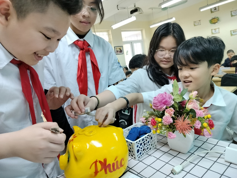 A group of kids putting money into a piggy bank

Description automatically generated